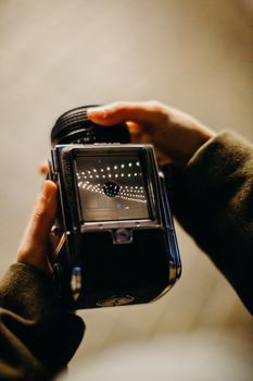 Detailed view of a person holding a vintage camera with focus on viewfinder.