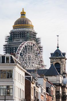 Scenic view of Brussels featuring the Palace of Justice and a Ferris wheel against a blue sky.