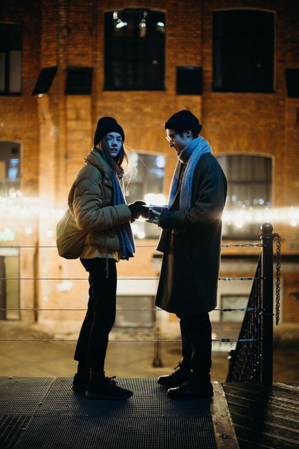 Stylish couple in winter attire during a night photoshoot in the city.