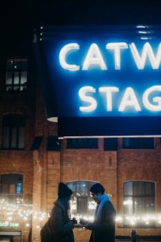 夜晚，两个人在霓虹灯招牌下交谈，营造出充满活力的城市氛围