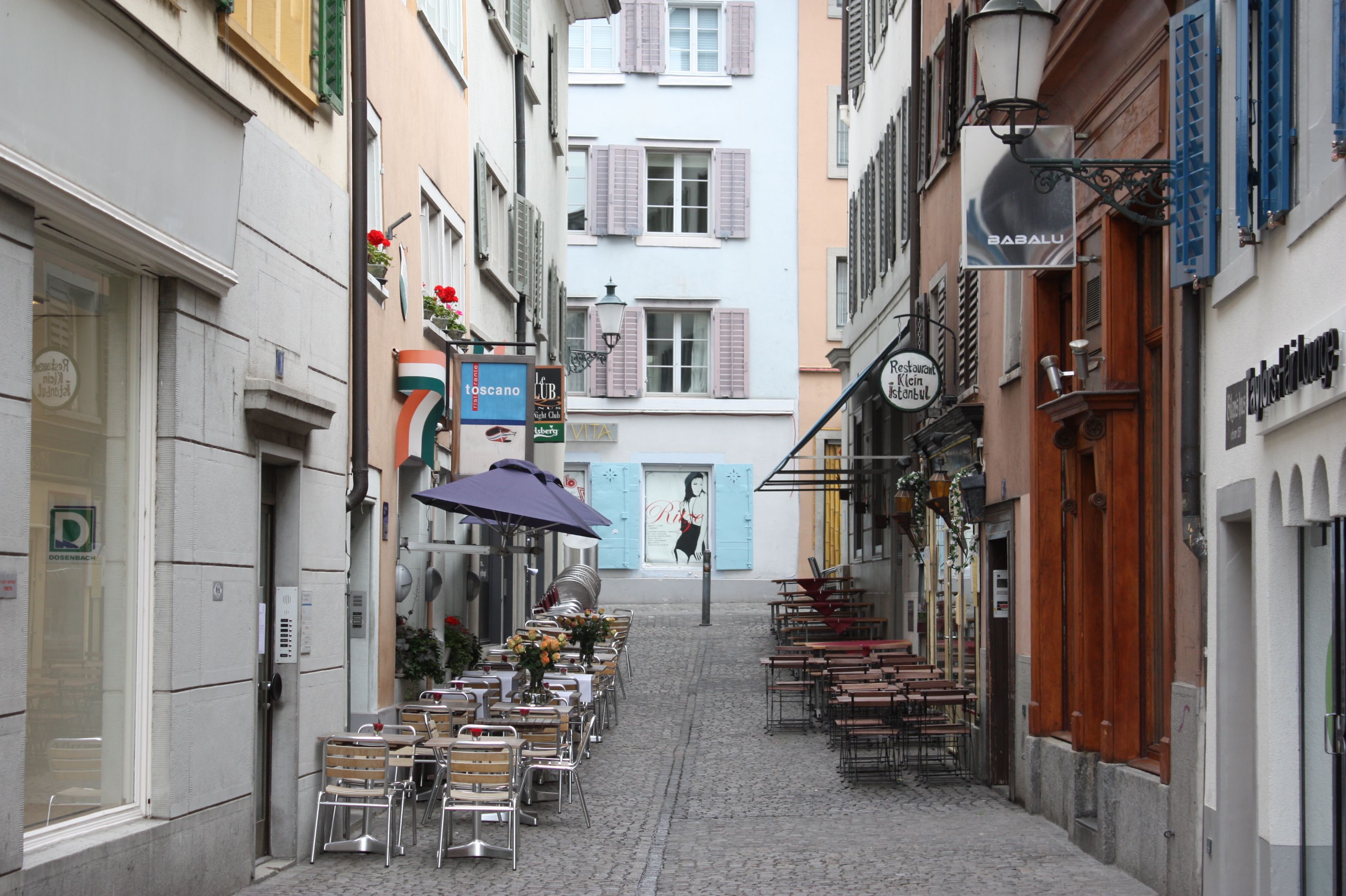 Person relaxing at a cafe table with coffee on a sunny European street