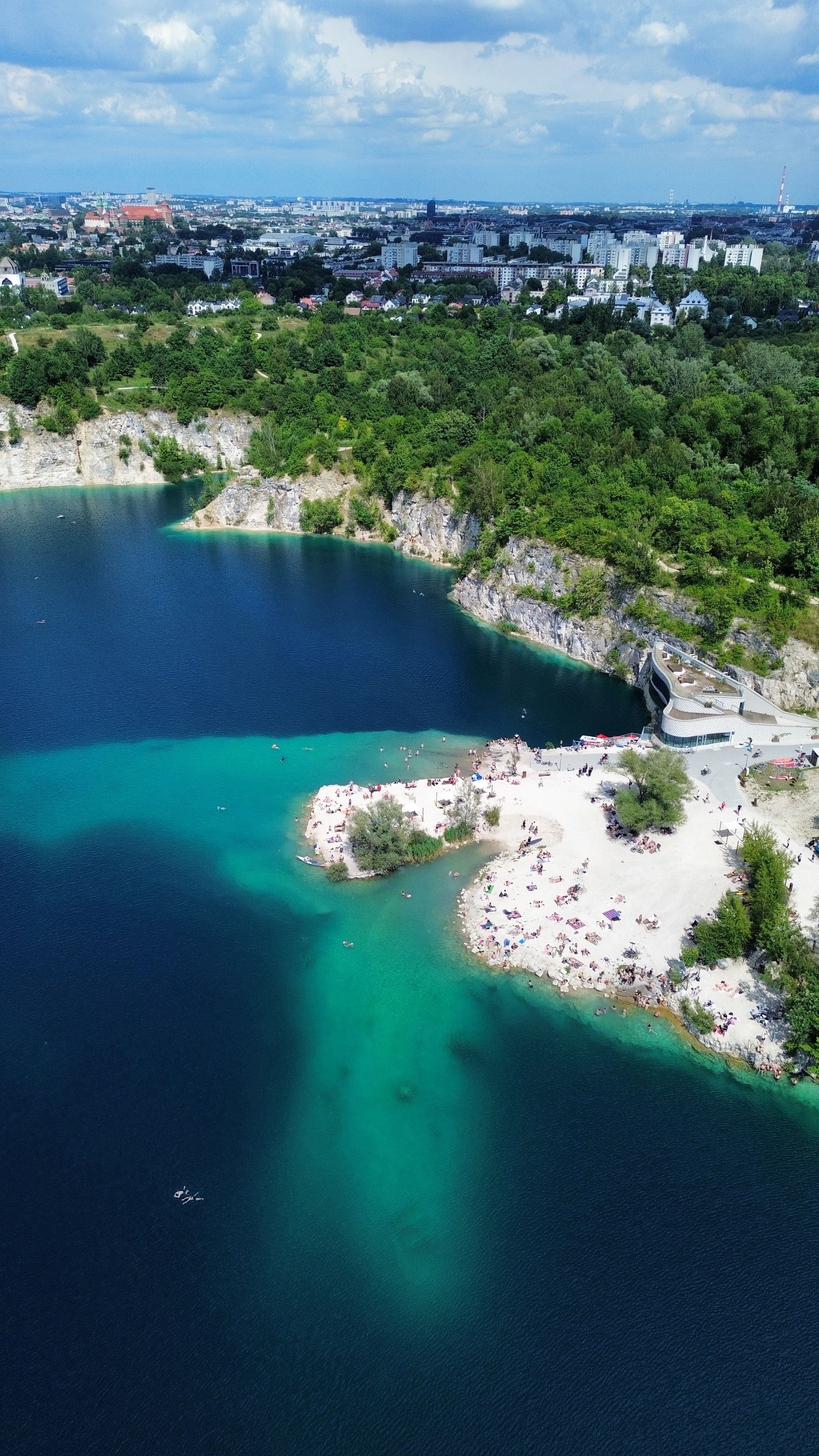 Stunning aerial shot of a vibrant lake and lush greenery with a distant city skyline.
