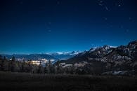 在迷人的星光之夜，俯瞰明亮的城镇和山峦背景