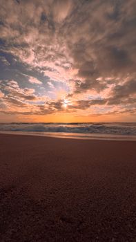 Stunning view of a sunset on a sandy beach with dramatic clouds. Perfect for travel and nature themes.