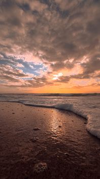 Stunning beach at sunset with dramatic clouds and gentle waves, capturing a serene coastal evening.
