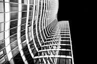 一张从低角度拍摄的现代摩天大楼黑白照片引人注目，其立面采用弧形玻璃设计