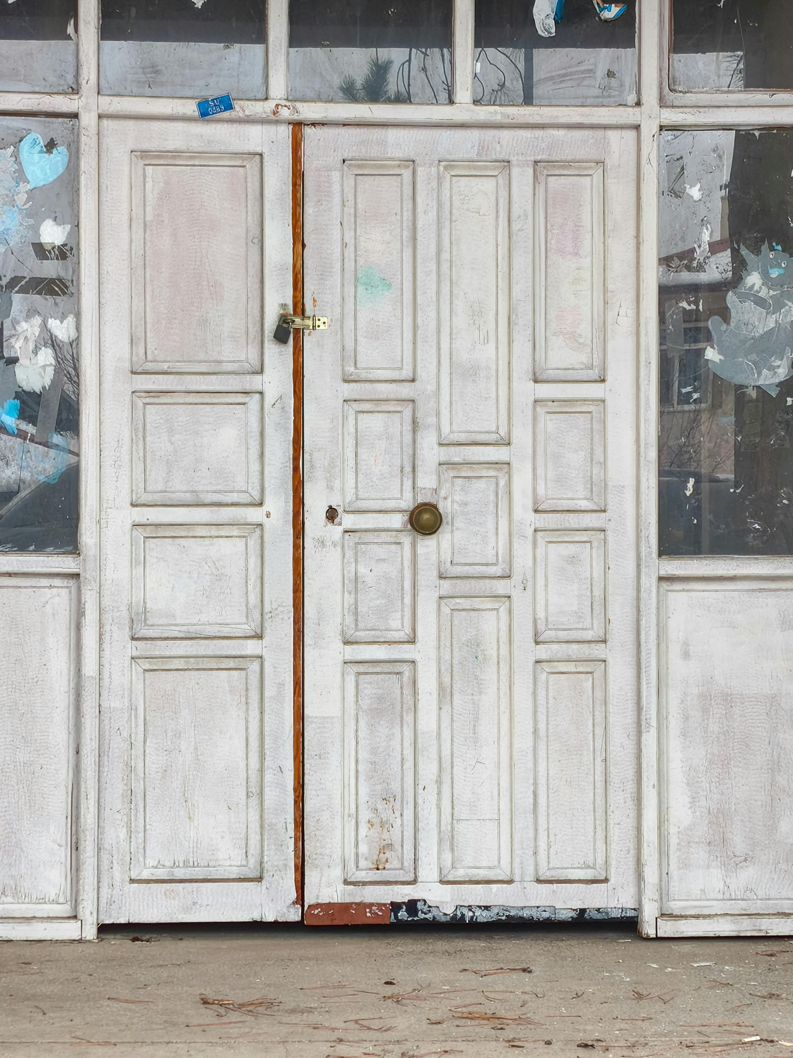 Gratis En rustikk, værbitt hvit dør med avskallet maling gir sjarm til en gammel bygningsfasade. Arkivbilde