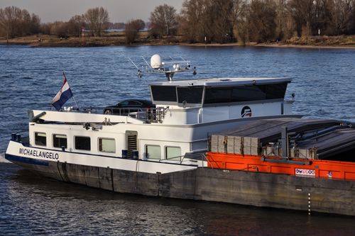 Free A cargo ship named Michaelangelo cruising the Rhine river on a sunny day. Stock Photo