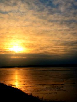Beautiful sunset casting golden reflections over a calm body of water with orange and blue sky.