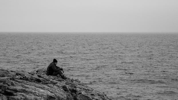A fisherman sits alone on a rocky shore in Kocaeli, Türkiye.