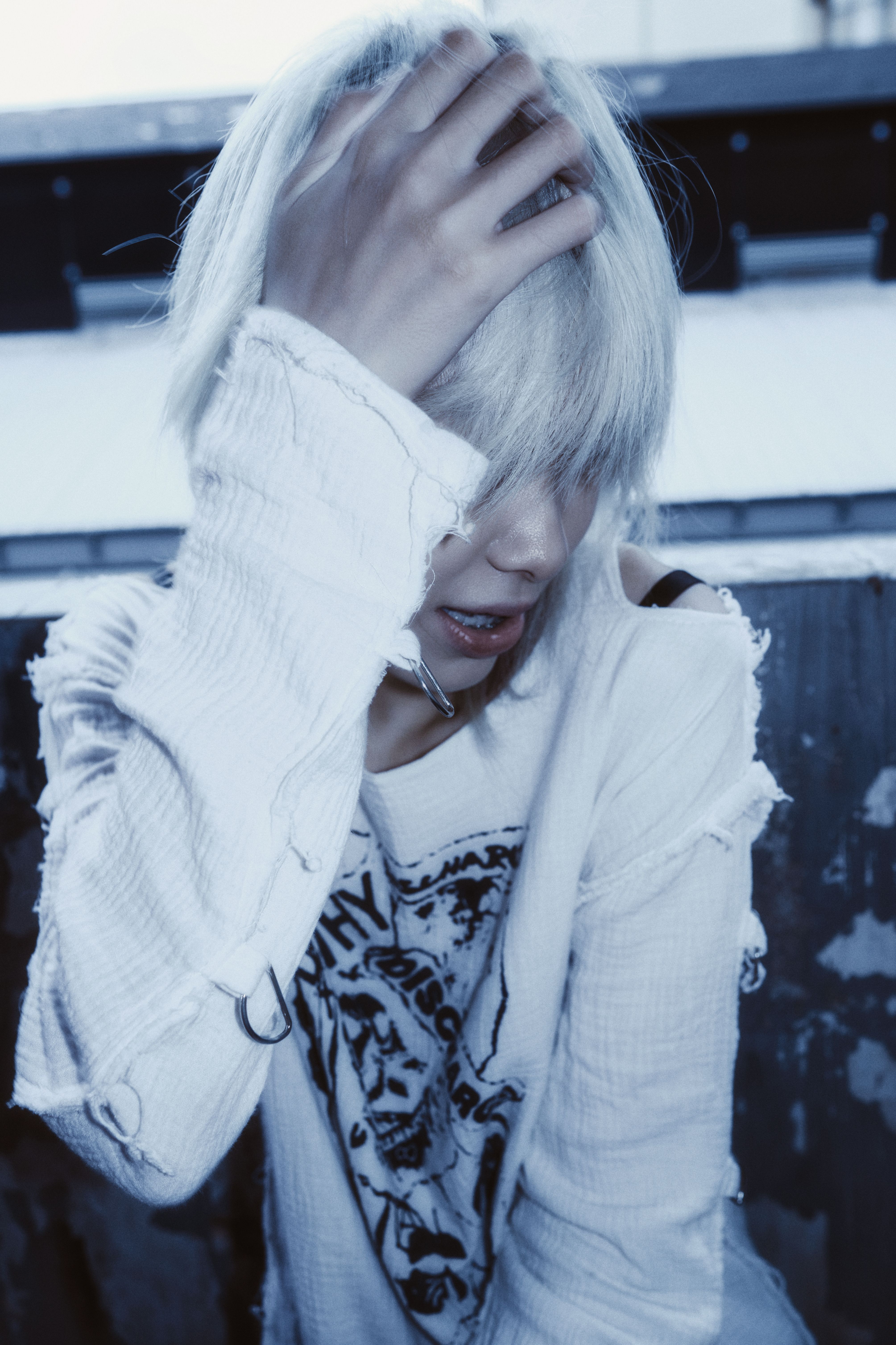 Fashionable person with platinum hair outdoors, wearing distressed clothing, creating a dramatic vibe.