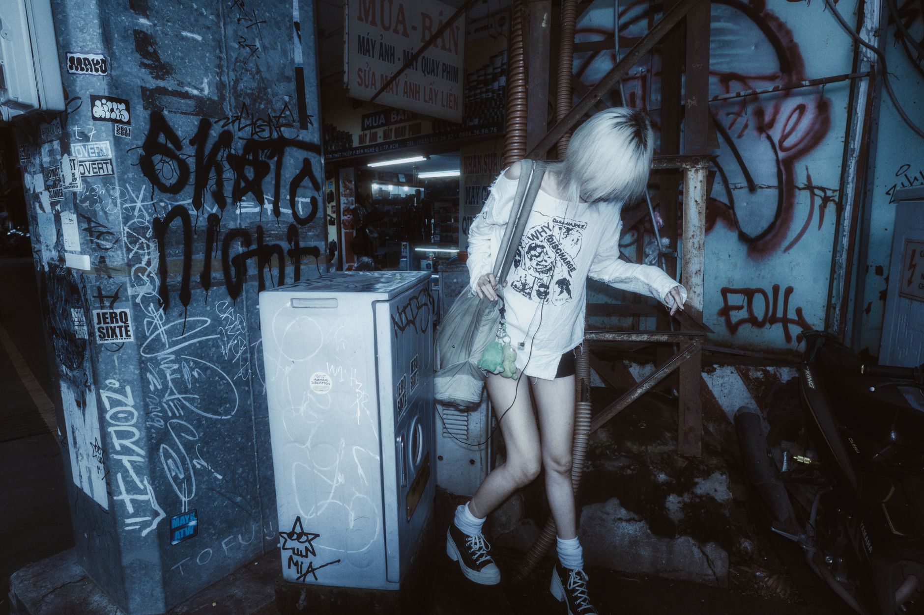 Young adult in urban graffiti setting with edgy street style at night.
