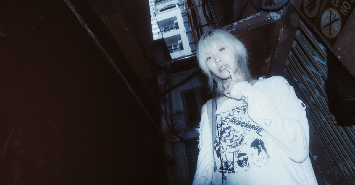 Young person with edgy style in dimly lit urban alleyway.