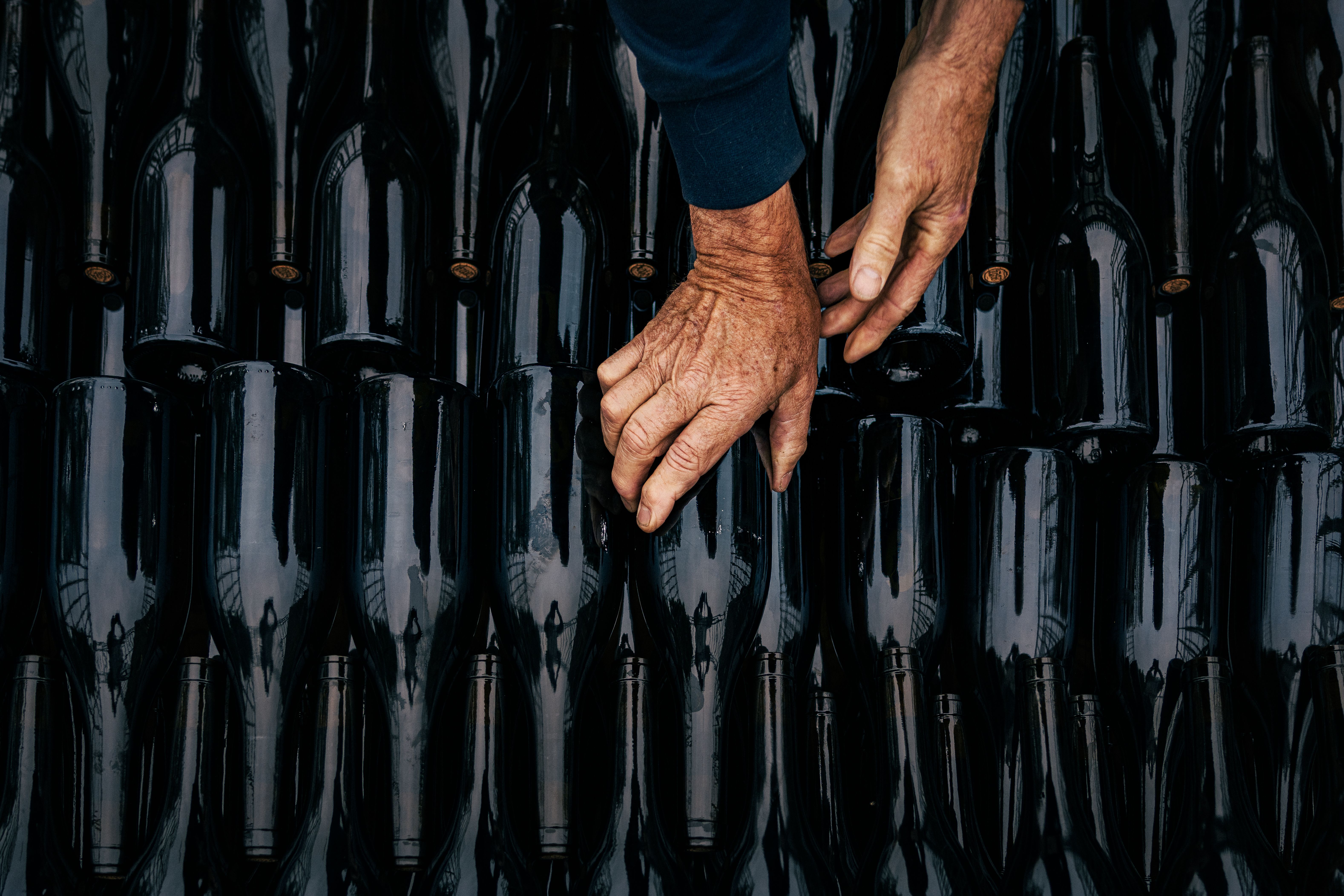 Close-up of hands organizing wine bottles in Nouvelle-Aquitaine's artisanal scene.