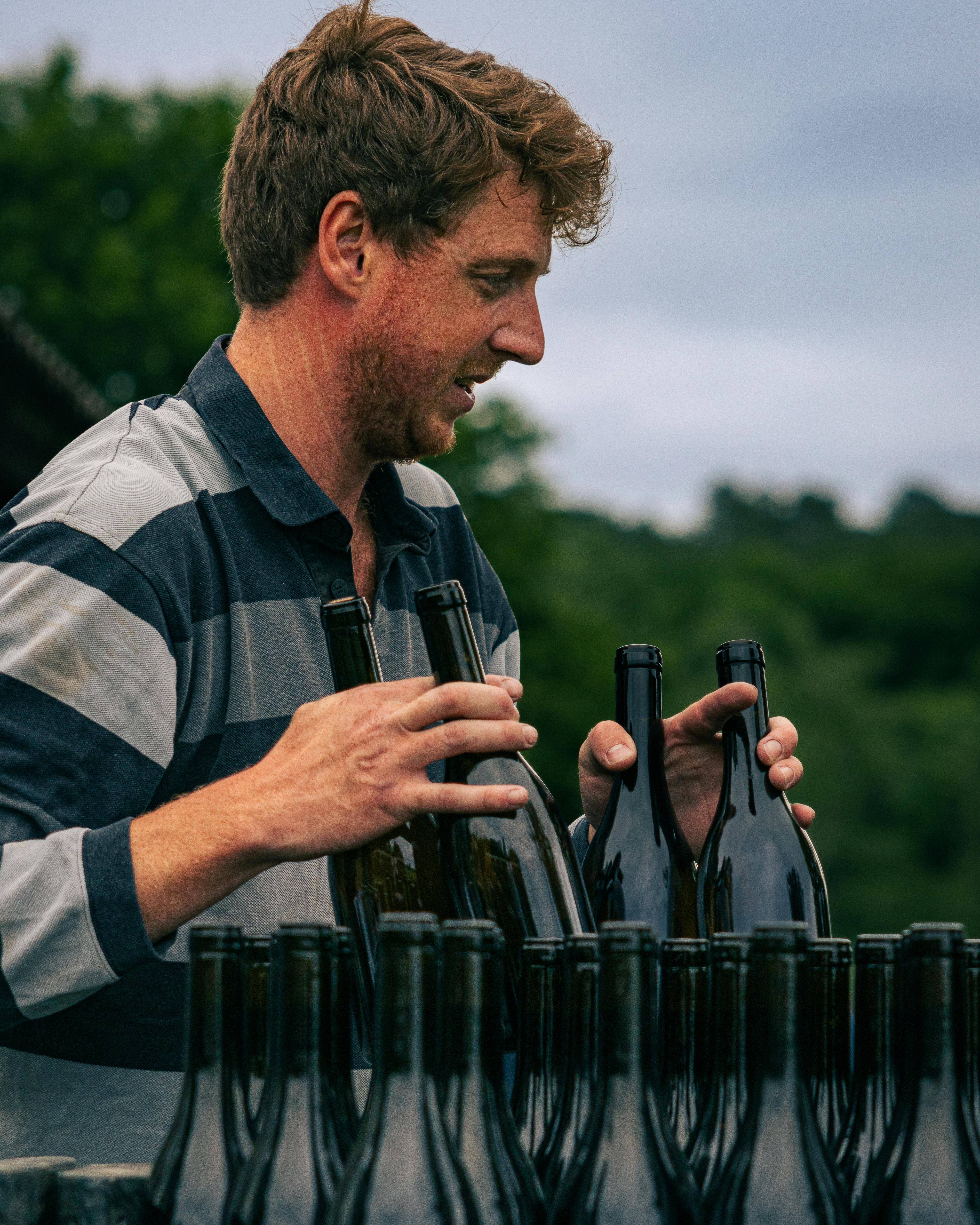 A male artisan in Nouvelle-Aquitaine arranges wine bottles, showcasing traditional craftsmanship.