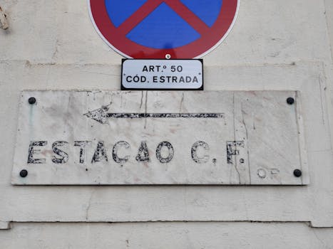 No parking sign with Portuguese C.F. station plaque on a wall in Águeda, Portugal.