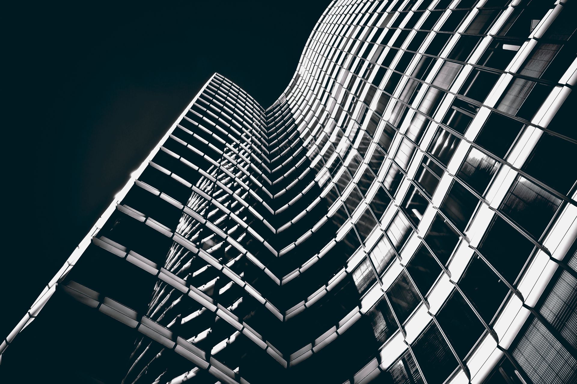 Curvaceous modern skyscraper facade in black and white, highlighting glass and steel elements.