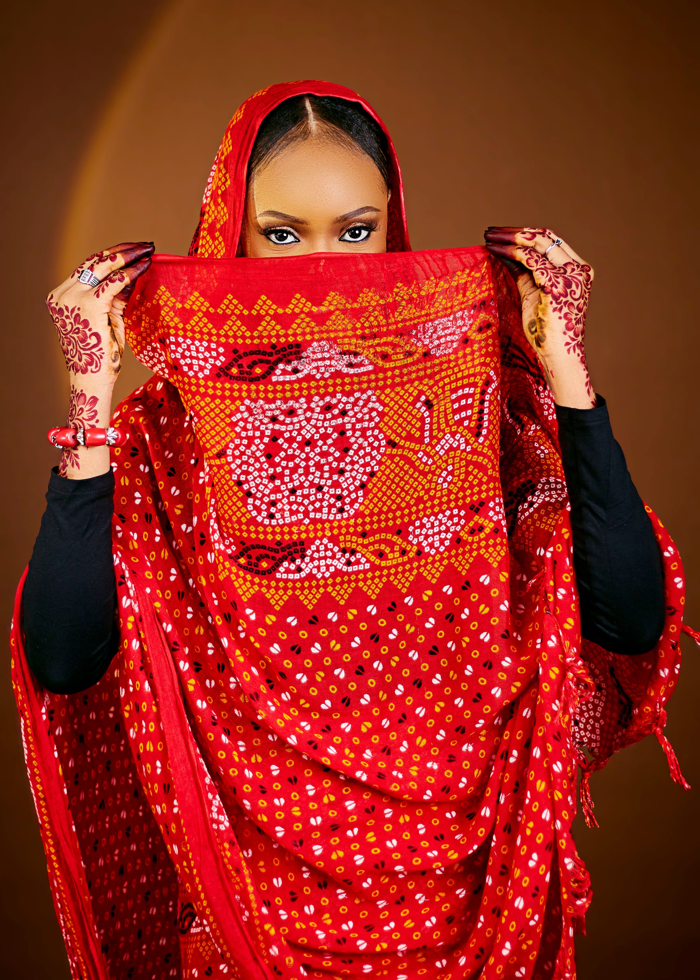 Captivating portrait of a woman in vibrant traditional attire with intricate henna design on hands.