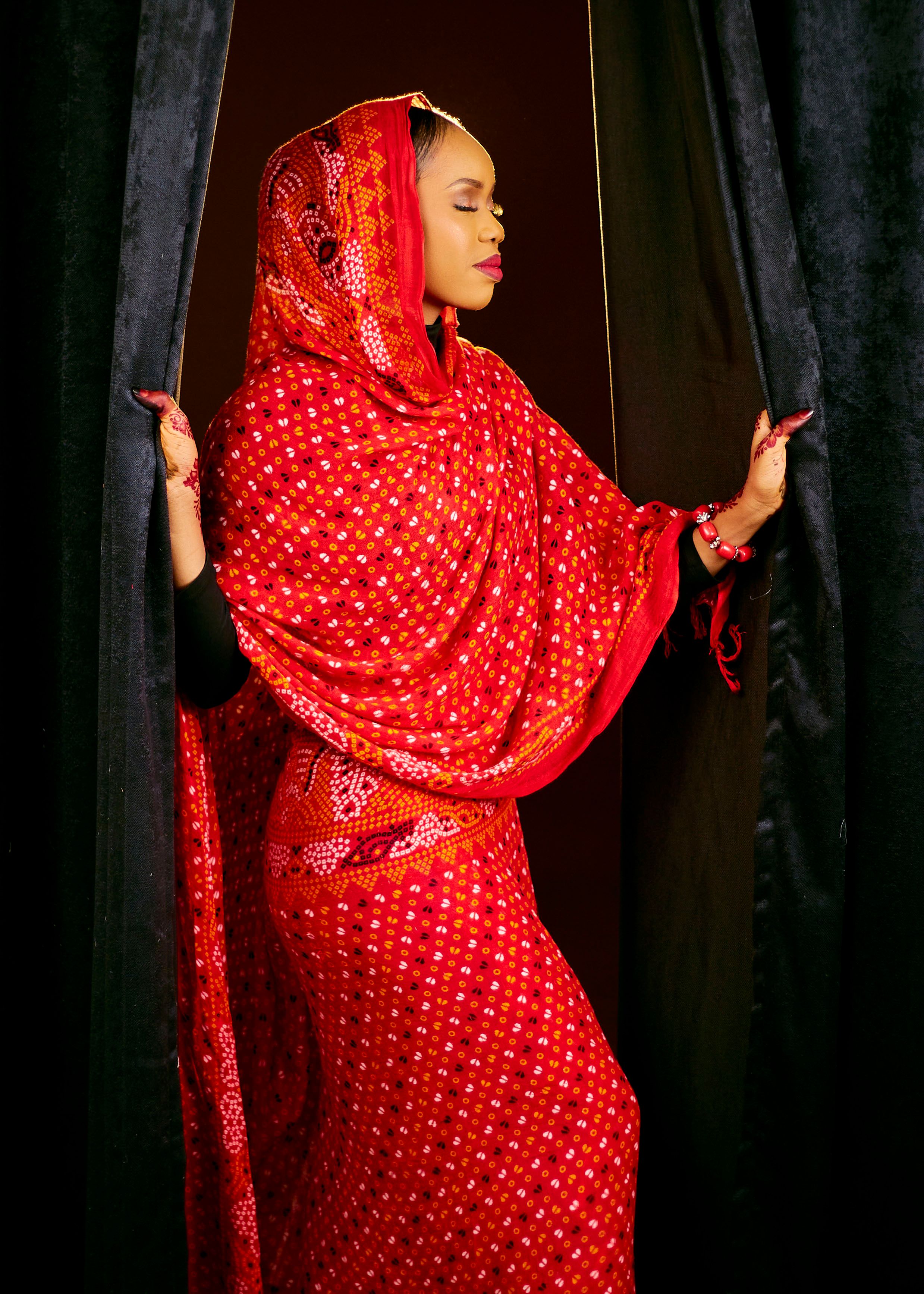 Portrait of a woman in a stunning, vibrant red traditional garment with intricate patterns.