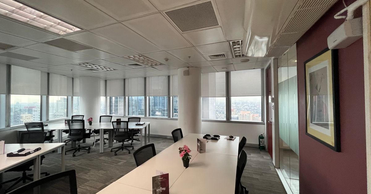A bright, spacious office interior with conference tables and cityscape view through large windows.
