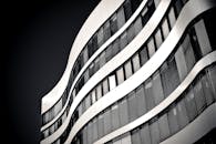 这张黑白照片中的现代高层建筑，拥有优雅的波浪形立面和玻璃窗