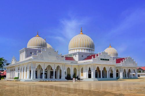 Free Elegant white mosque exterior with domes under blue sky in Aceh, Indonesia. Stock Photo