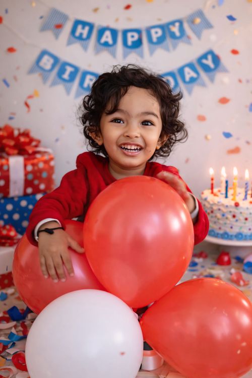 Free Smiling child surrounded by balloons at a joyful indoor birthday party. Stock Photo