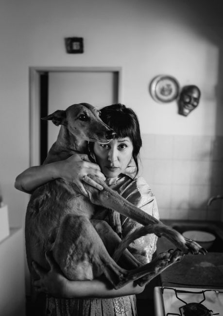 Heartfelt black and white portrait of a woman embracing a dog indoors.