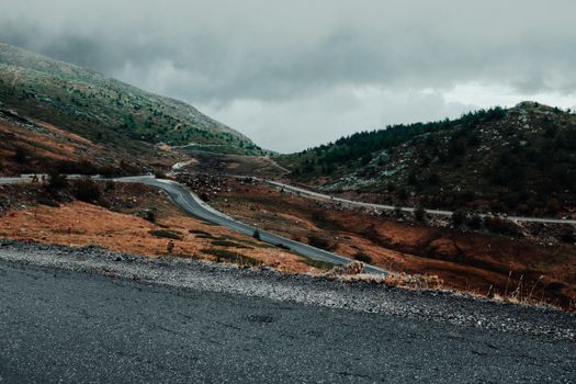 A scenic winding mountain road under a moody sky, perfect for adventurous travel themes.