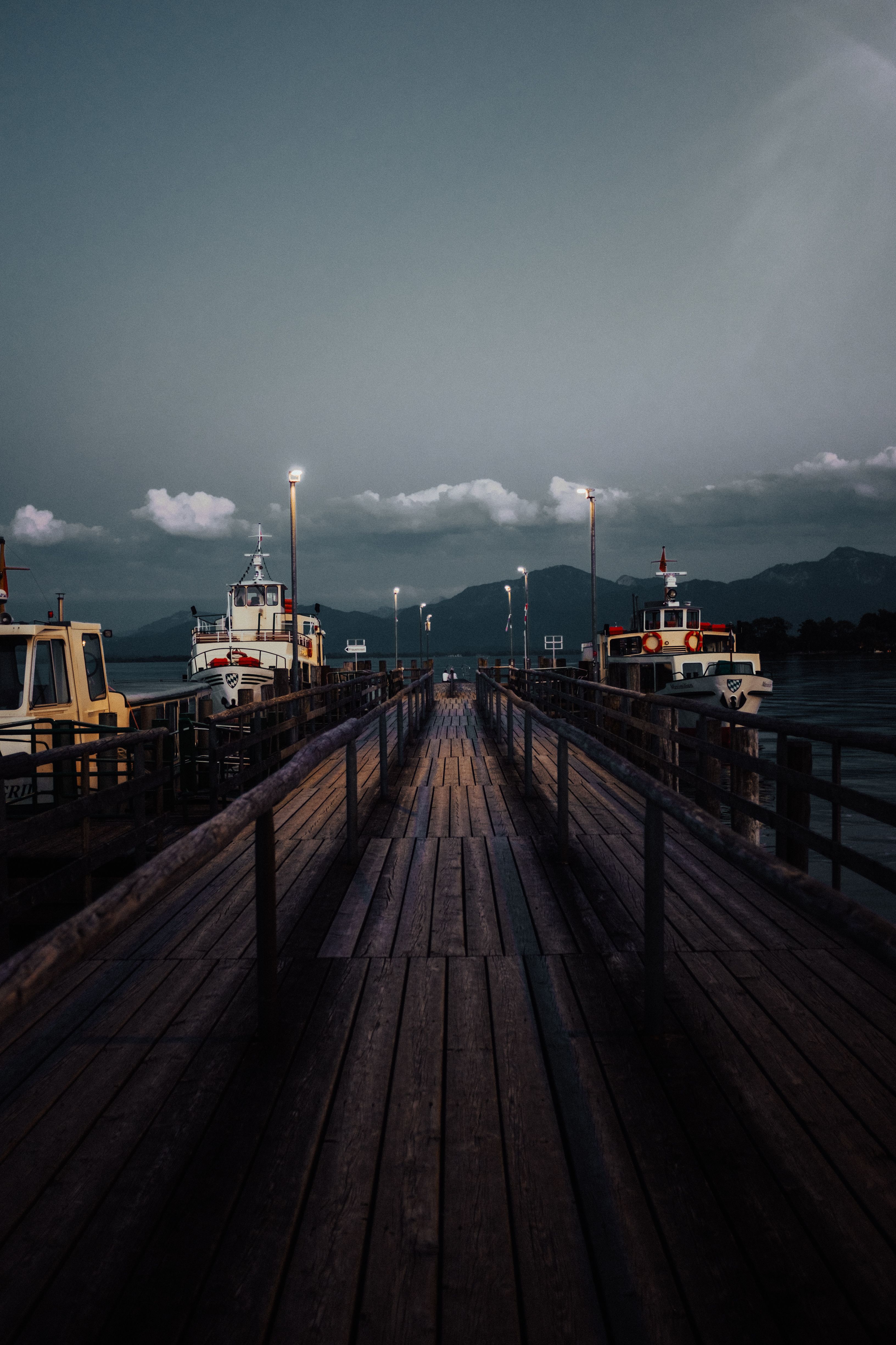 Ruhige Abendstimmung an einem See mit Booten und Bergen – Landschaftsfotografie von Tasso Mitsarakis