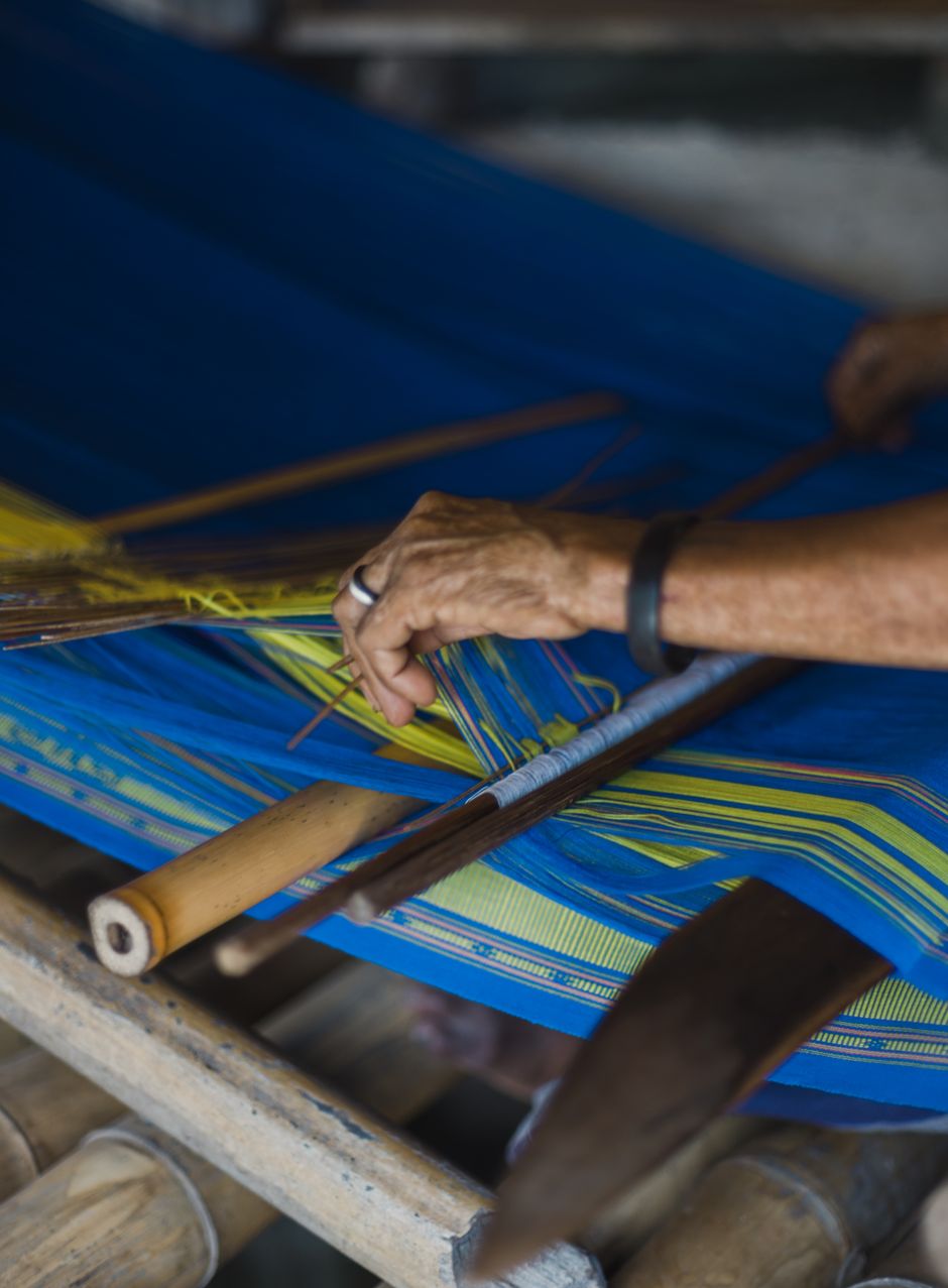 Hands weaving indigo and citron thread on a backstrap loom — photo by Agung Pandit Wiguna on Pexels