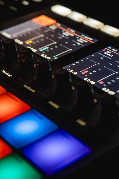 Free Close-up of a music production controller with vibrant backlit pads and knobs, ideal for audio mixing and digital production. Stock Photo