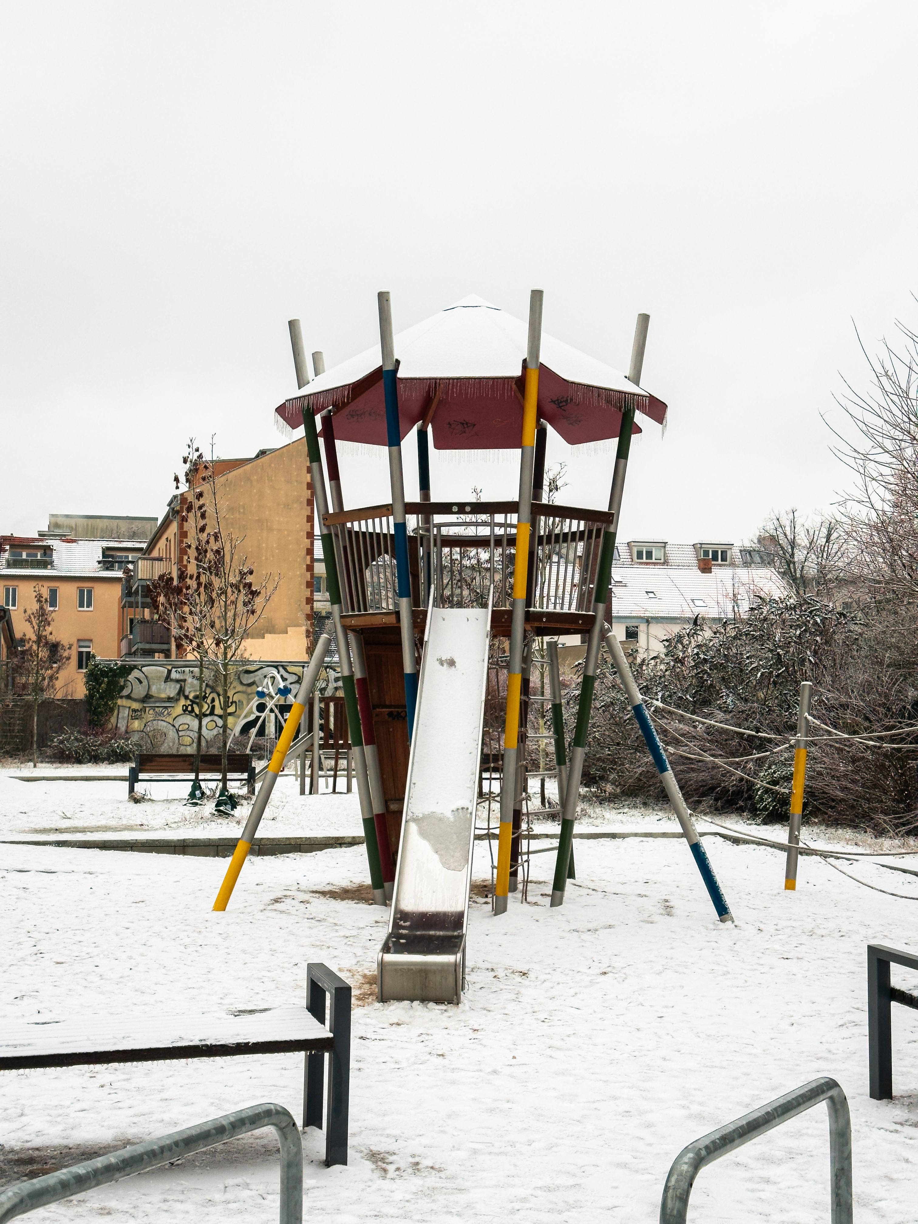 Gratis Parco giochi innevato con scivolo, che mostra una serena giornata invernale all'aperto. Foto a disposizione