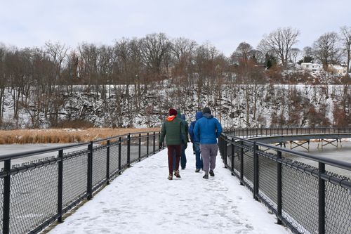 Free People walking on a snowy bridge in a scenic winter landscape. Stock Photo