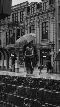 Black and white street photo of a rainy day in Gent, featuring a person with an umbrella.
