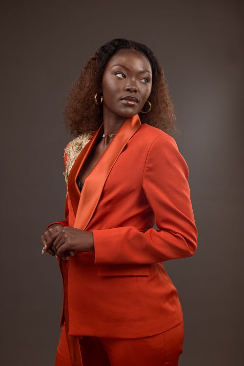 Free Stylish woman in orange blazer posing confidently against a neutral background. Stock Photo