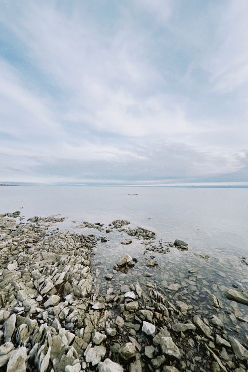 Free Peaceful rocky shoreline of a lake under a cloudy sky in Konaev, Kazakhstan. Tranquil and natural setting. Stock Photo