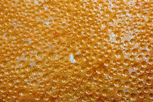 Free Macro shot of dew droplets on an orange-colored textured surface, creating a vibrant pattern. Stock Photo
