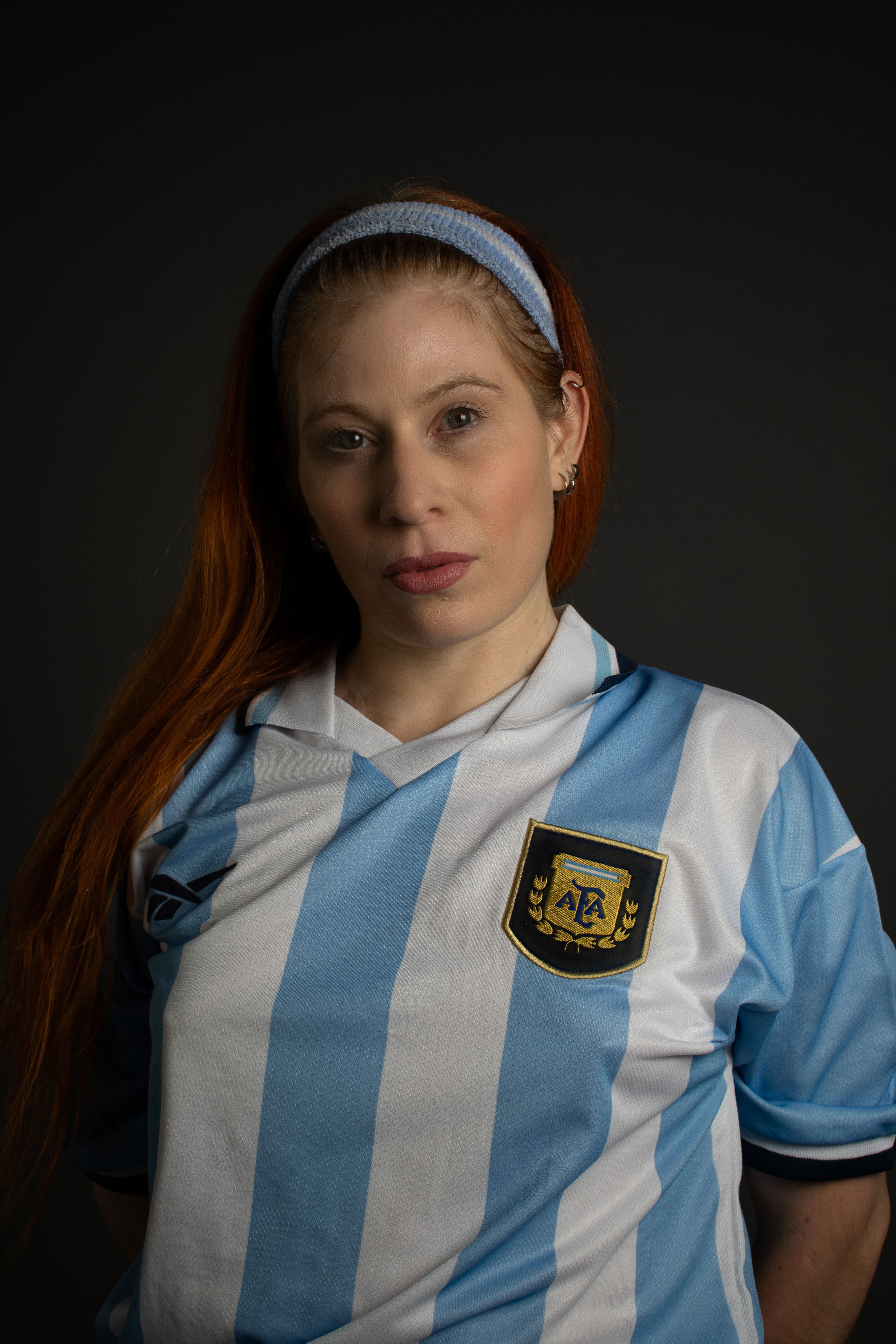 Woman wearing an Argentina football jersey with a thoughtful expression.