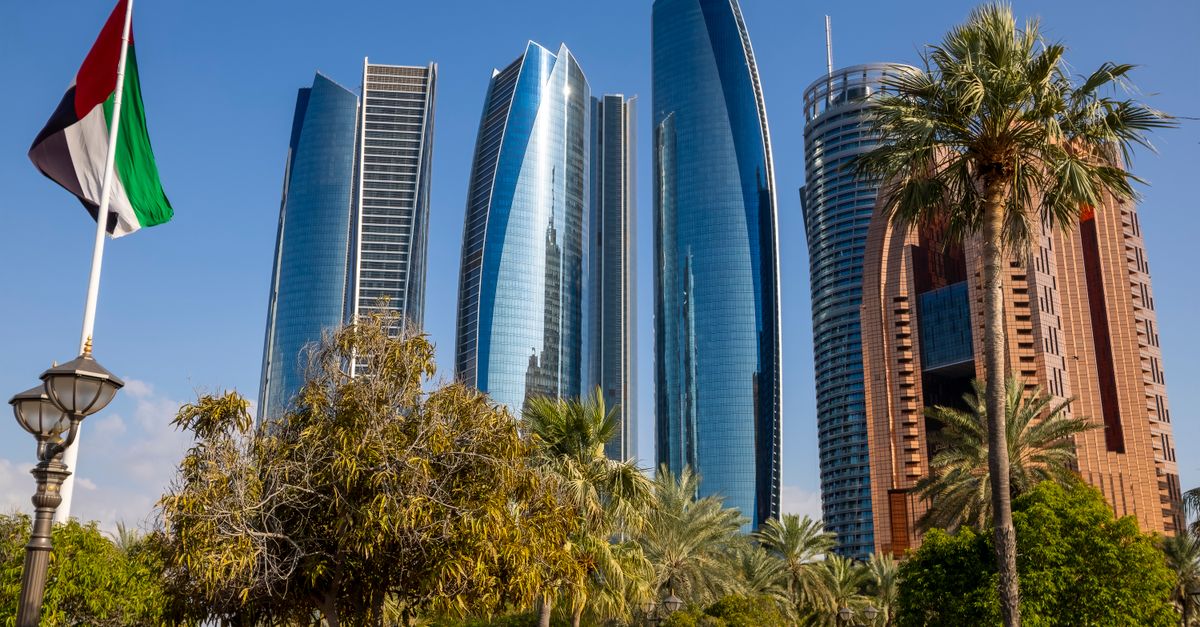 Captivating shot of the iconic Etihad Towers, Abu Dhabi landmark with palm trees and UAE flag.