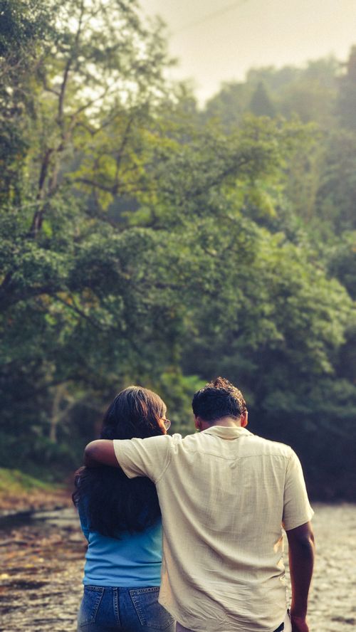 Free A couple lovingly embraces by a serene river in a lush Kerala forest. Stock Photo