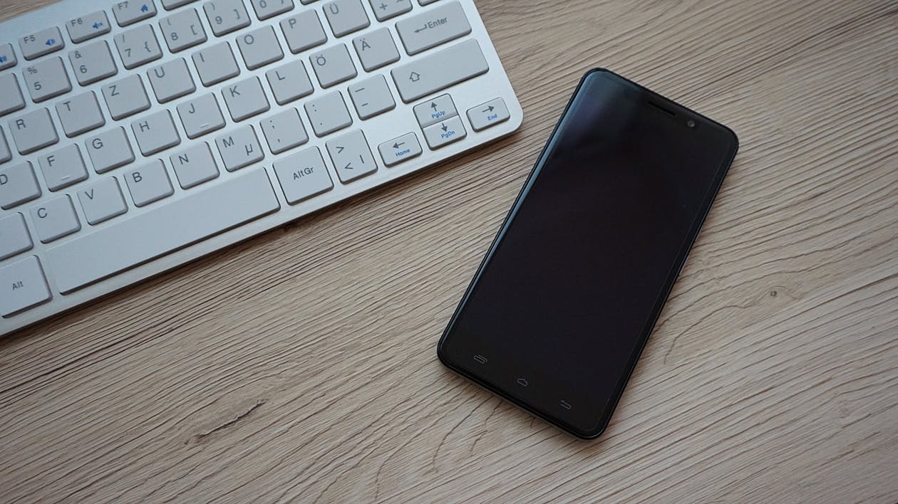 無料 Apple Magic Keyboardの近くにある黒いスマートフォン 写真素材