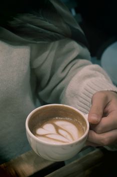 Cozy winter moment with latte art in a mug, perfect for coffee lovers.
