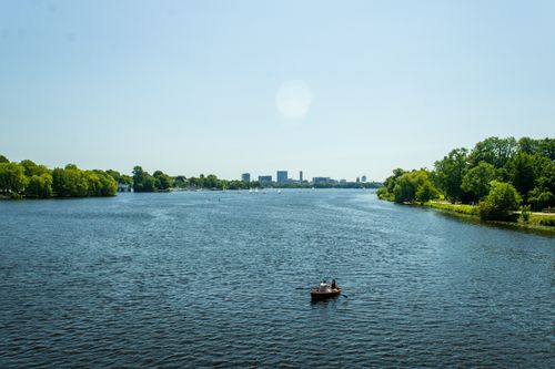 Free View of Alster Lake with rowboat and city skyline in Hamburg, Germany. Stock Photo