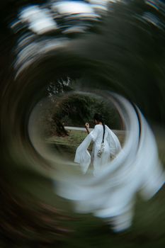A woman in white walks through a blurred mystical forest, creating a dreamy effect.