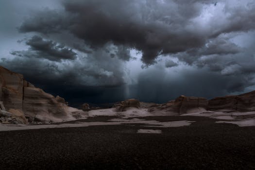 Majestic storm clouds gather over a rugged desert landscape, creating a dramatic and moody scene.