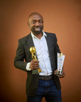 Smiling businessman holding two awards, symbolizing achievement and success.