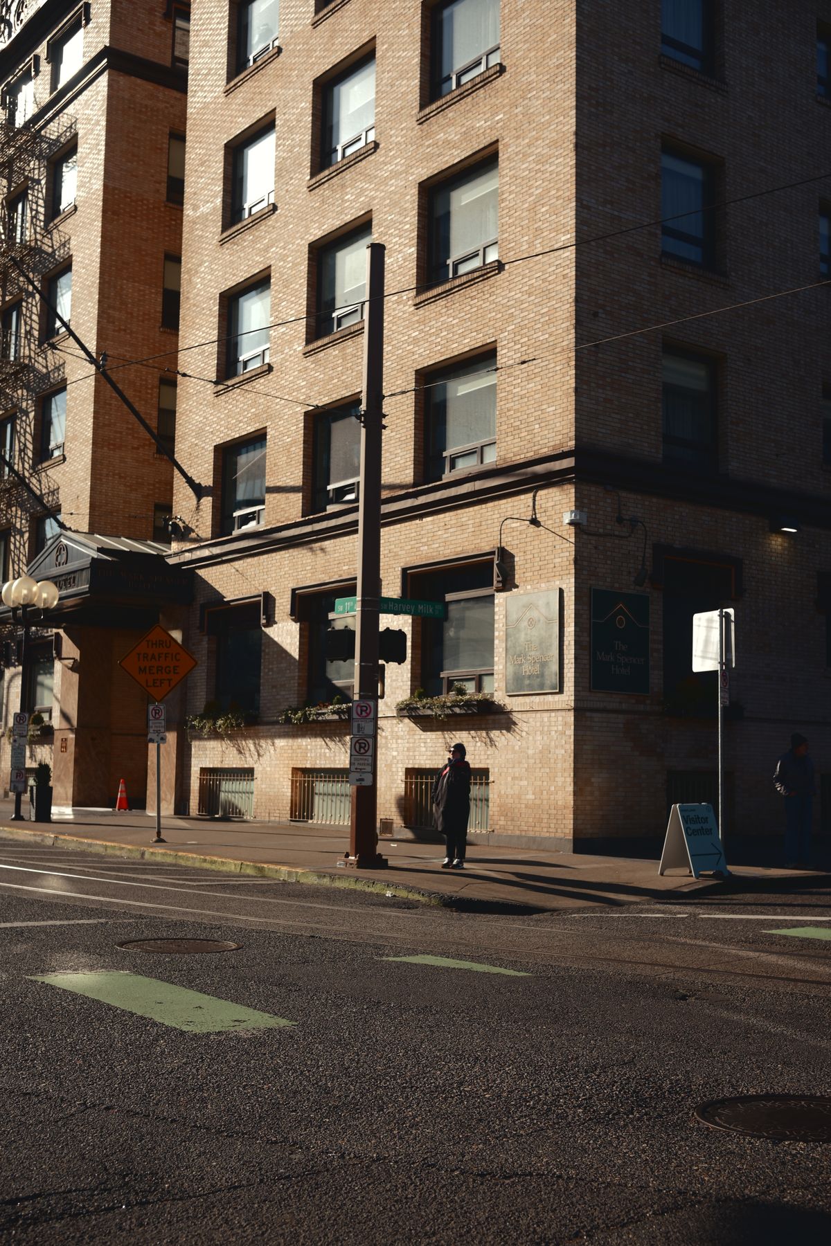 A person walking across the street in front of a tall building · Free ...
