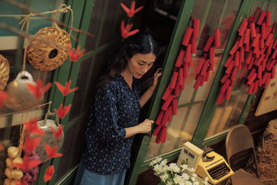 Portrait of a woman surrounded by vibrant red decorations and vintage elements indoors.