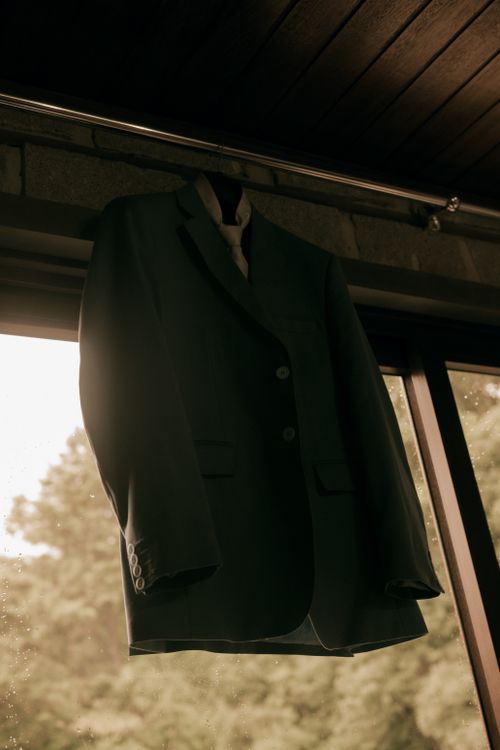 Free Elegant blazer hanging by the window with outdoor view, highlighting fashion style. Stock Photo